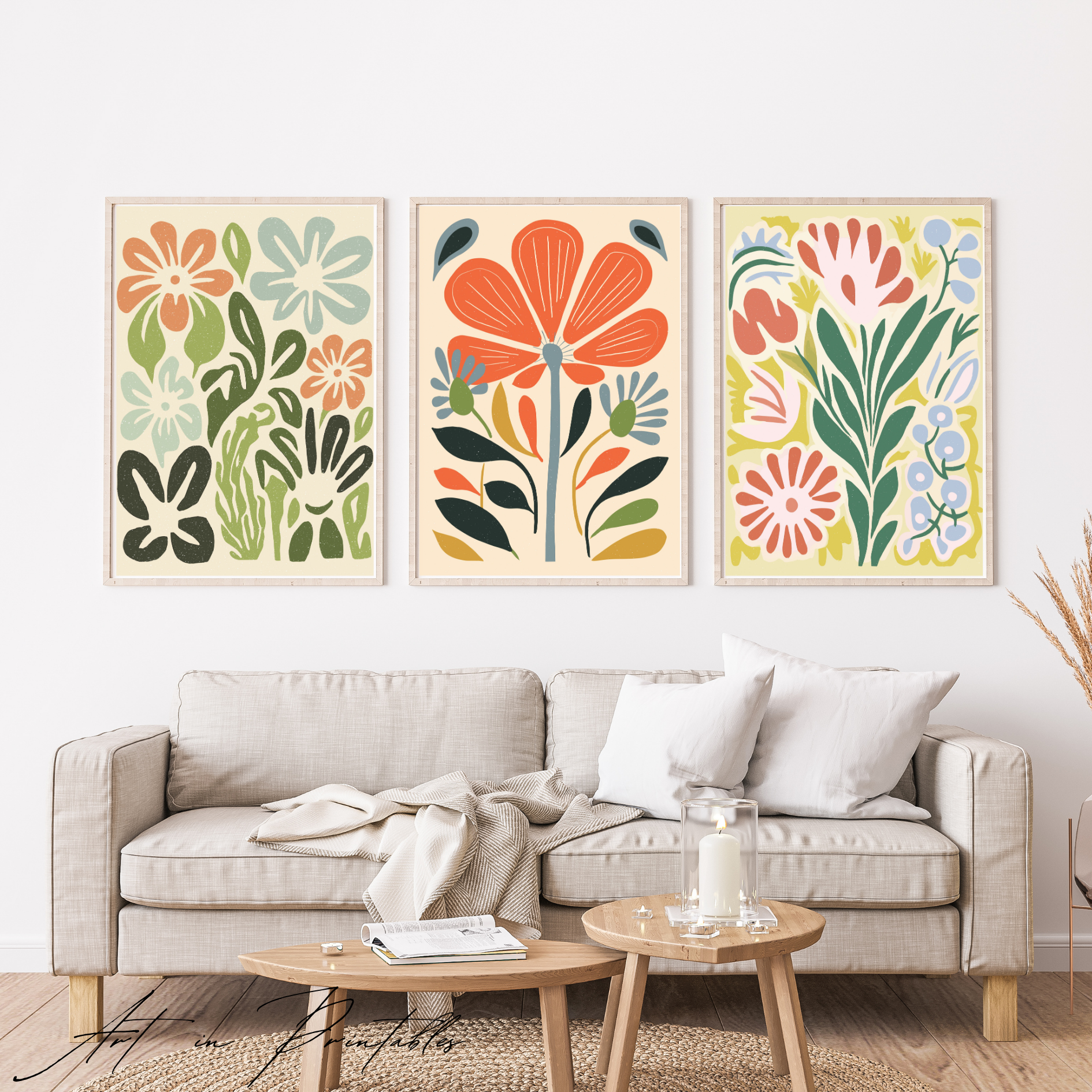 Three colorful floral prints above a beige sofa in a living room setting.