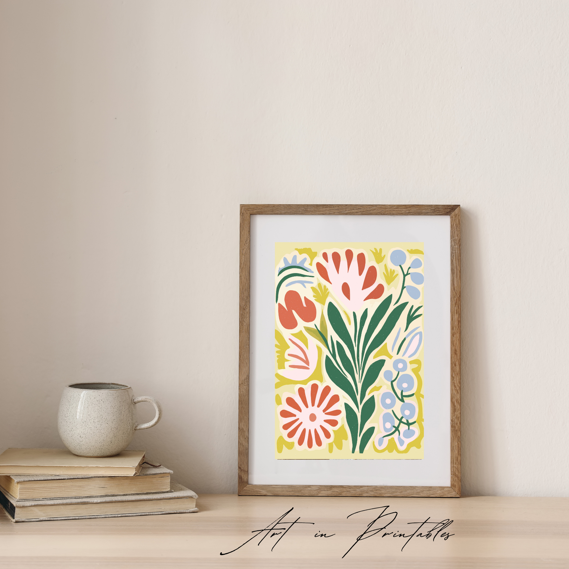 Framed floral artwork on a wall with books and a mug below.
