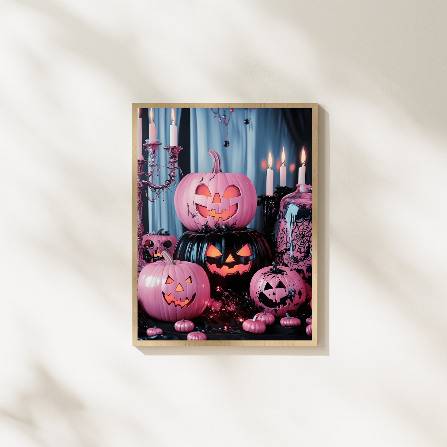 Framed Halloween-themed artwork with pink jack-o'-lanterns and candles on a white wall.